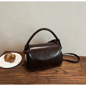 Detail of a chocolate brown glossy leather bag with embossed Eleanor branding