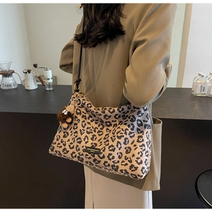 Detail of leopard print tote bag with plush charm and black wide shoulder strap
