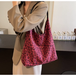 Close-up of leopard print tote bag with pink base color and black slim straps on a model