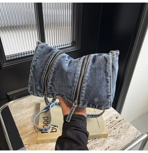 Close-up of blue denim tote bag showing vintage washed texture and zipper details