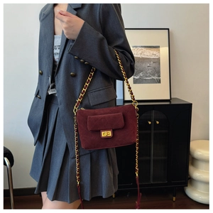 Detail of burgundy suede shoulder bag with gold twist lock and woven chain strap