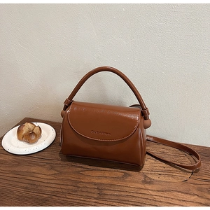 Detailed view of caramel patent leather bag with CLEAROK lettering on a wooden desk