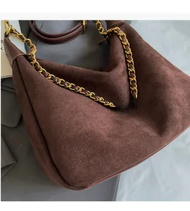 Detail of dark brown matte suede hobo bag with gold chain and leather woven strap