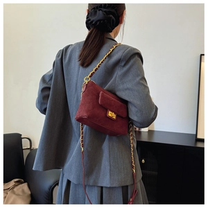 Detail of burgundy quilted suede handbag with gold chain strap and metal swivel clasp