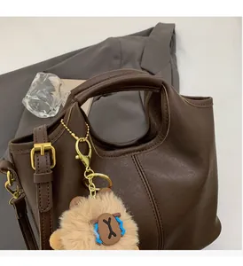 Close-up of the sturdy brown faux leather handle and gold metal hardware on the handbag