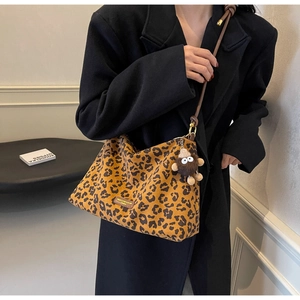 Detailed view of leopard print tote bag with plush charm and slim leather strap