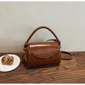 Detailed macro shot of brown vintage hand-held square bag with CLEAROK logo on wood desk