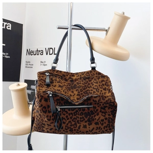 Vue détaillée du sac cabas léopard avec poches zippées sur un support en métal