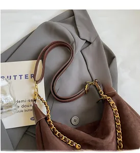 Macro view of dark brown frosted suede hobo bag with gold metal chain strap on a blazer