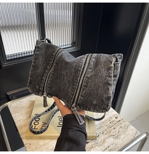 Close-up of dark grey washed denim tote bag featuring vintage metal zipper details