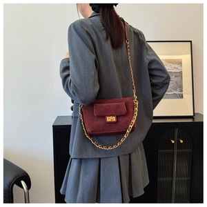 Detail of burgundy quilted suede shoulder bag with gold chain strap and twist-lock buckle
