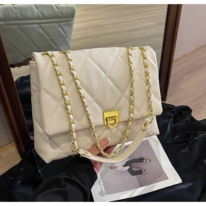 Detailaufnahme der cremefarbenen Stepptasche mit goldenem Drehverschluss und Kettenriemen