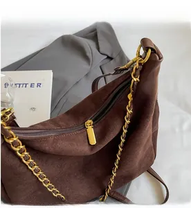 Close-up of smooth gold zipper and chain on brown suede shoulder bag for women