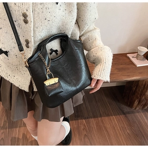 Détail du sac cabas noir vintage avec chaîne dorée et mini pochette sur le côté