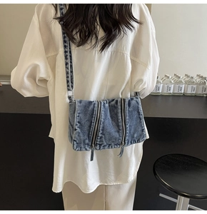 Blue denim tote bag with dual metal zippers worn with a stylish casual outfit