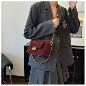 Detail of burgundy quilted leather bag with gold twist lock and chain strap on a model