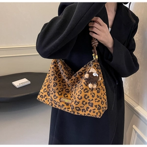 Detail of leopard print tote bag featuring brown leather knotted strap and plush charm