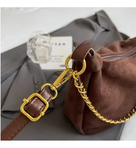 Detail of dark brown matte leather handbag with gold metal chain and buckle