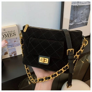 Close-up of black quilted suede bag with elegant golden turn-lock and chain strap