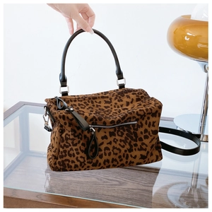 Détails d'un sac cabas léopard avec poignées en cuir noir et fermeture éclair argentée
