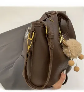 Close-up of brown leather bag showing premium gold hardware and furry ball charm