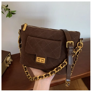 Close-up of brown suede crossbody bag with quilted stitching and gold chain strap