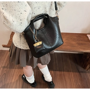 Close-up of black embossed PU leather bucket bag with gold chain and mini pouch detail