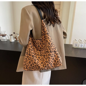 Close-up of leopard print tote bag with black strap on a model in a warm setting