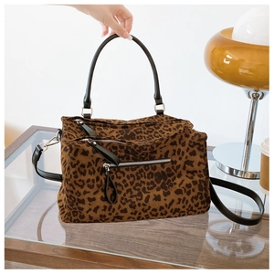 Détail du sac léopard avec poignées en cuir noir et fermeture éclair décorative sur le devant