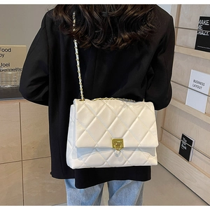 Nahaufnahme weiße Stepptasche mit goldener Kette auf schwarzem Blazer-Outfit