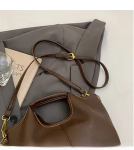 Detail of adjustable long shoulder strap and golden hardware on dark brown leather bag
