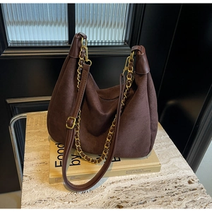 Detail of dark brown matte hobo bag with gold metal chain and leather shoulder strap