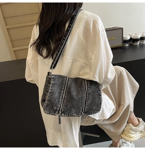 Detail of grey washed denim tote bag with multi-zipper design and adjustable strap