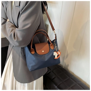Close-up of waterproof nylon tote with leather handles and a horse-shaped pendant charm