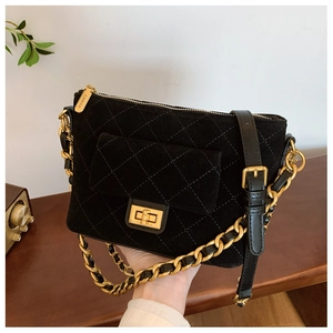 Detailed shot of a black quilted crossbody bag with a gold twist lock and metal chain