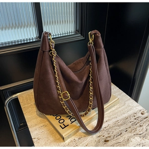 Detailed view of matte dark coffee suede hobo bag with vintage gold chain on marble base