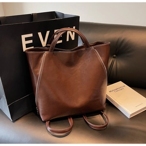 Detail of deep brown PU leather tote with visible white stitching and zipper accents