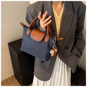 Close-up of contrast large tote bag with navy nylon body and brown leather handles