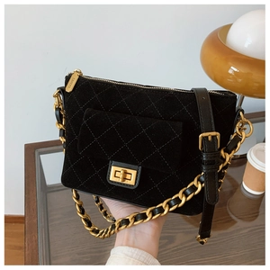 Detailed close-up of black quilted shoulder bag with golden twist lock and woven chain strap