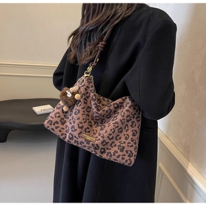 Detail of leopard print hobo bag with brown plush monkey charm and dark leather strap