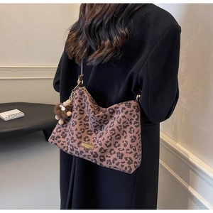 Detailed shot of large leopard print tote bag featuring a cute plush monkey keychain