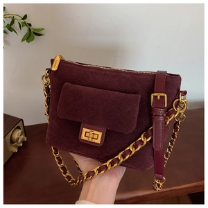 Detail of burgundy suede crossbody bag with gold-tone hardware and diamond quilting pattern
