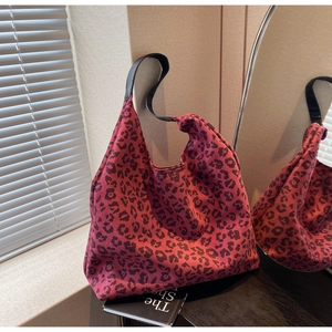 Detail of red leopard print tote bag on a book with blurred mirror reflection background