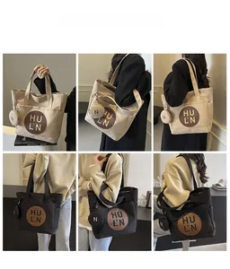 Detail view of large canvas tote bag with leather logo patch and matching mini pouch