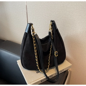 Detail of matte black suede hobo bag with vintage gold chain and smooth leather trim