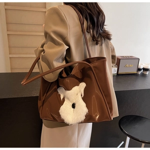 Detail of brown leather tote bag with plush Schnauzer puppy patch and long shoulder strap
