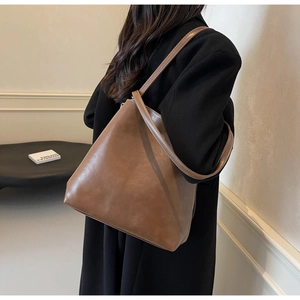 Detail of vintage brown leather tote bag with white stitching on a model's shoulder