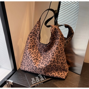 Close-up of a large leopard print tote bag with black leather straps and hobo design