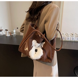 Brown leather tote bag featuring a plush Schnauzer patch shown on model in a cafe