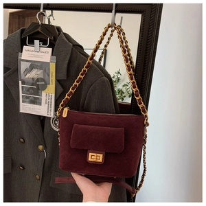 Detail of burgundy quilted suede bag with gold twist lock and metal chain strap